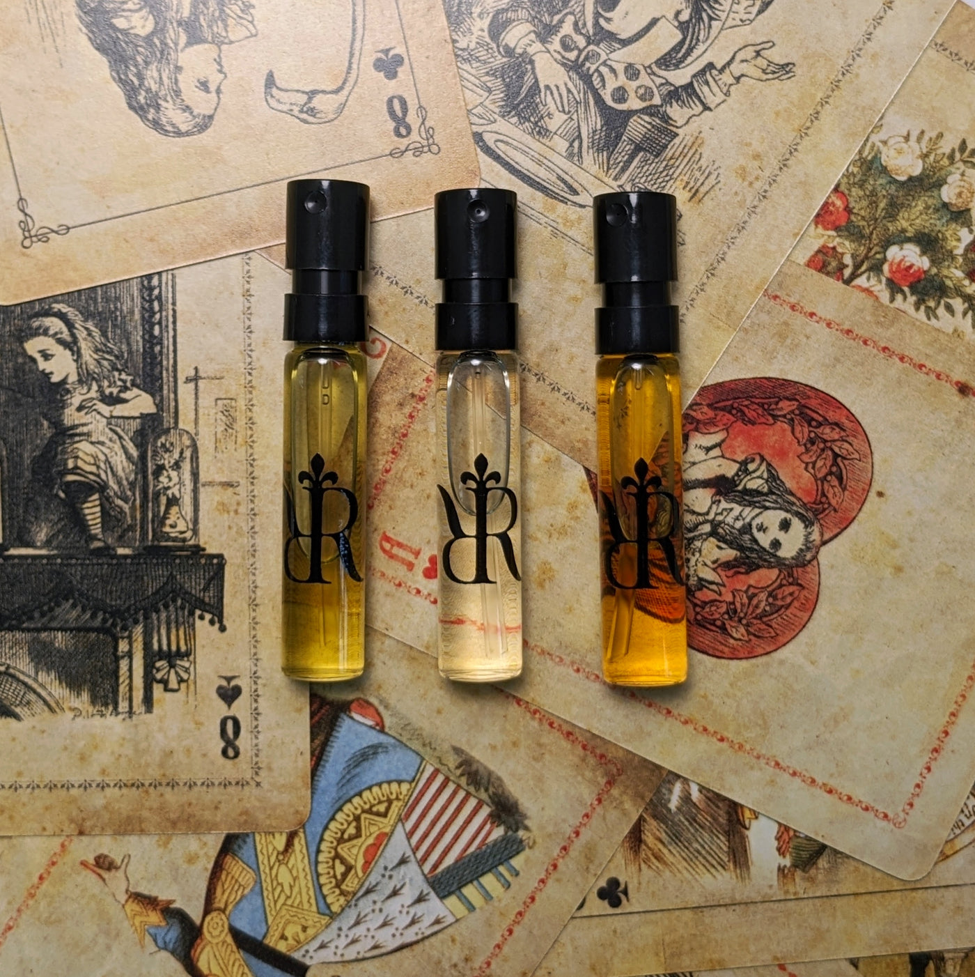 Perfume samples lay in front of Alice's Adventures in Wonderland playing cards.