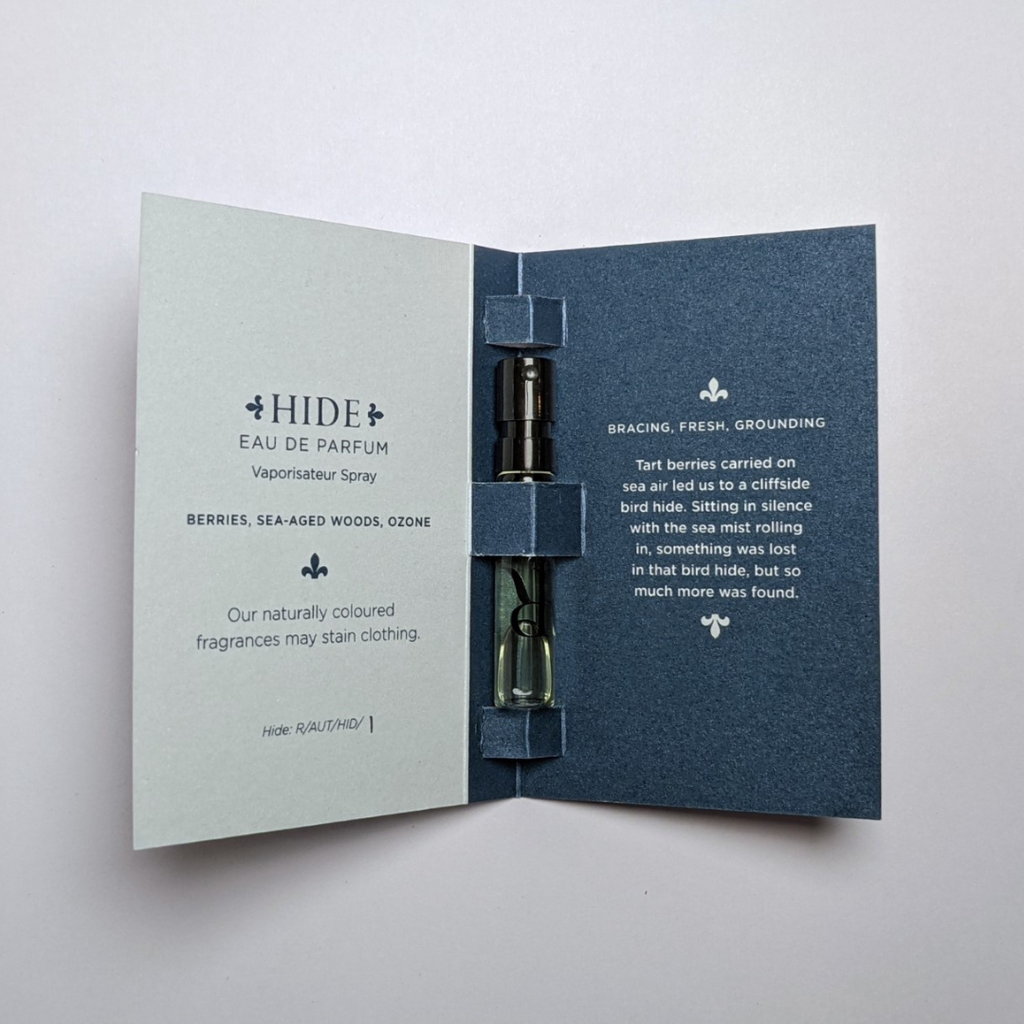 Sample card with niche perfume Hide by Redolescent. It is a misty blue colour with a 2ml sample vial inside.
