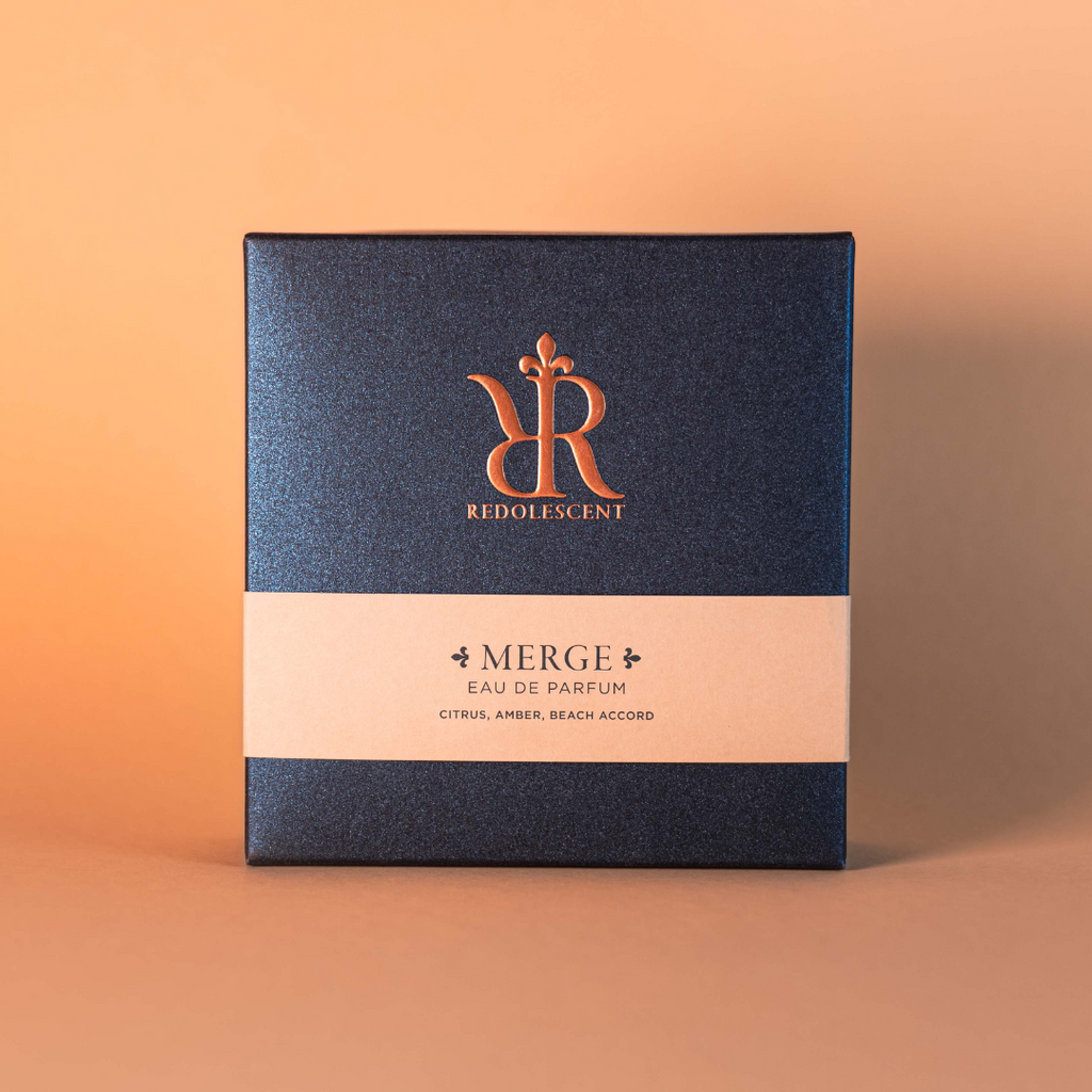 Packaging for niche perfume Merge, glittery blue with an embossed logo and a peach band across the middle.